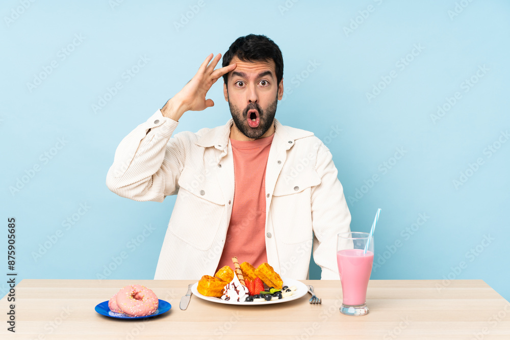 Man at a table having breakfast waffles and a milkshake has just realized something and has intending the solution Man at a table having breakfast waffles and a milkshake has just realized something and has intending the solution