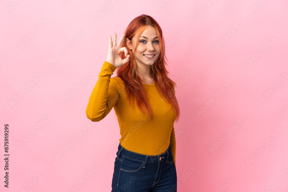 Teenager Russian girl isolated on pink background showing ok sign with fingers Teenager Russian girl isolated on pink background showing ok sign with fingers
