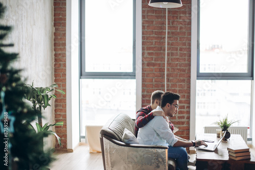 Two male buddies sitting in modern loft design office looking at laptop and discussing business ideas. photo