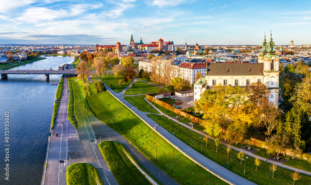 Krakow, Poland. Aerial old city autumn skyline with Skalka church, far view of Wawel castle and cathedral, Vistula river with a bridge, boulevards and promenades with trees, pedestrians and cyclists