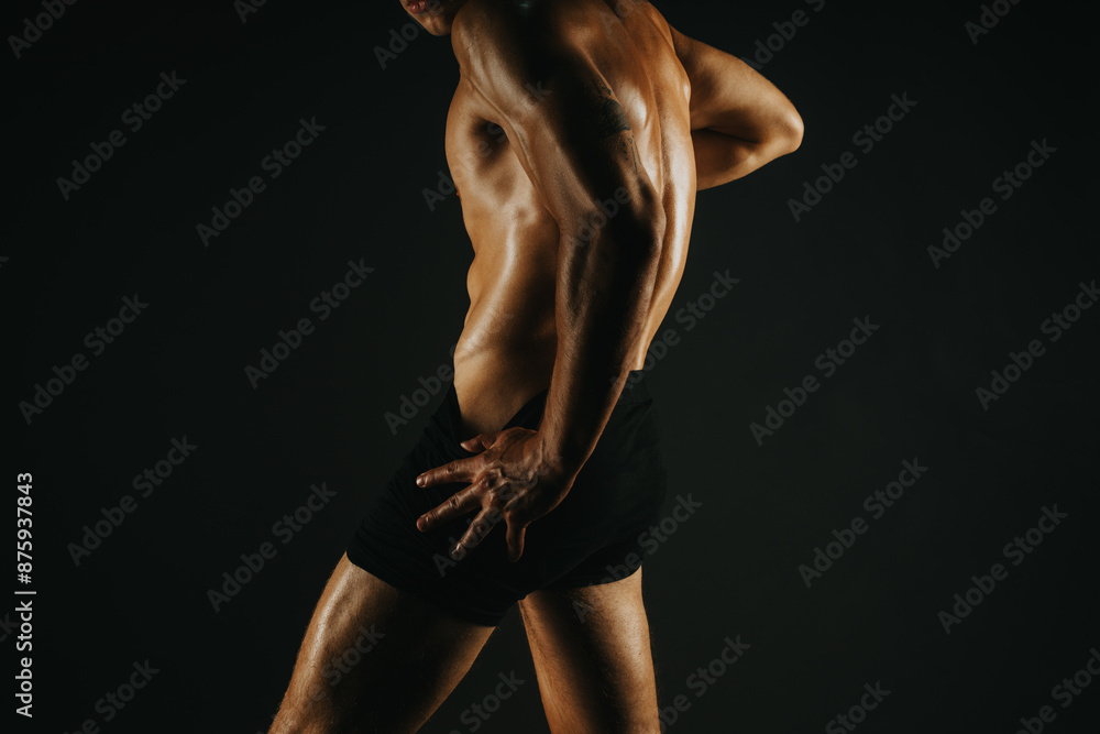Fit man showcasing his defined back muscles in a dark, dramatic studio setting. Ideal for fitness, health, body art, and strength concepts. Fit man showcasing his defined back muscles in a dark, dramatic studio setting. Ideal for fitness, health, body art, and strength concepts.