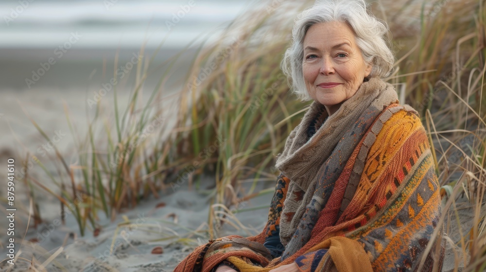 Senior woman wearing shawl sitting on beach