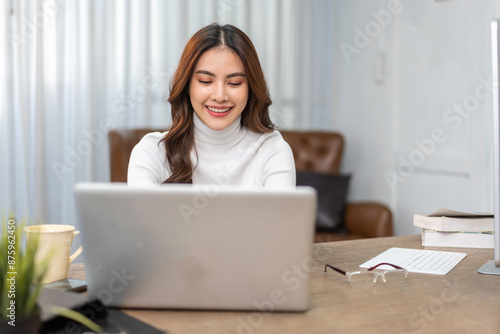 Young smiling asian woman relax using laptop conference work,learning education,study online,webinar podcast,creative woman looking at screen, shopping, online marketing at home