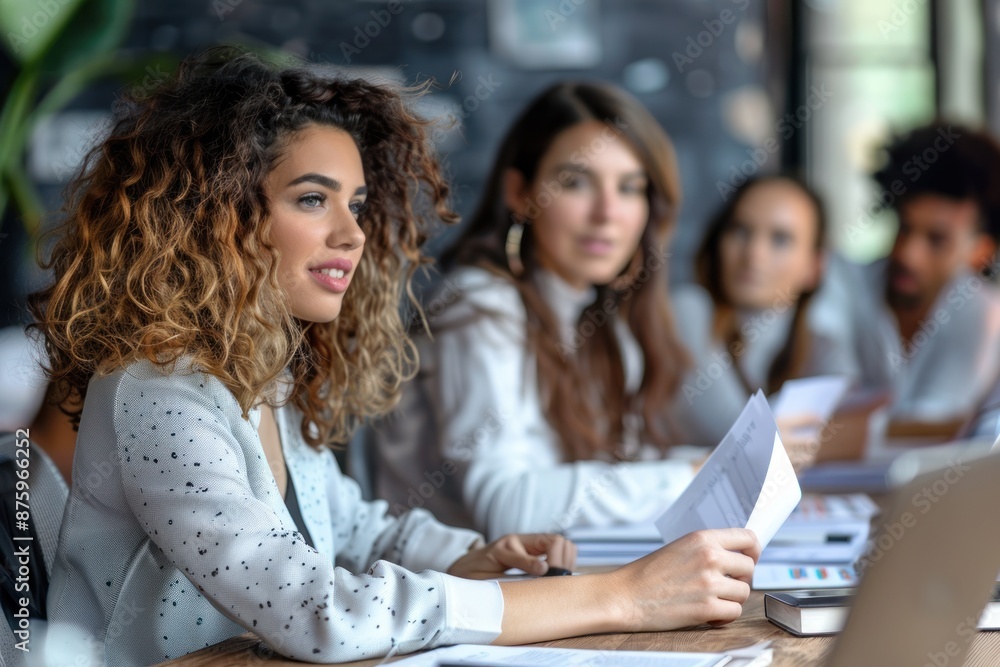 A beautiful business woman sitting on a meeting next to a table with her colleagues and handing a paper to someone A beautiful business woman sitting on a meeting next to a table with her colleagues and handing a paper to someone