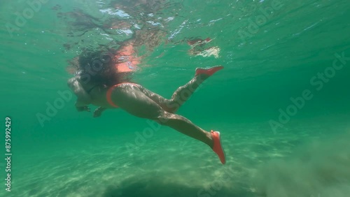 Underwater slow motion clip of young woman swimming in clear sea water