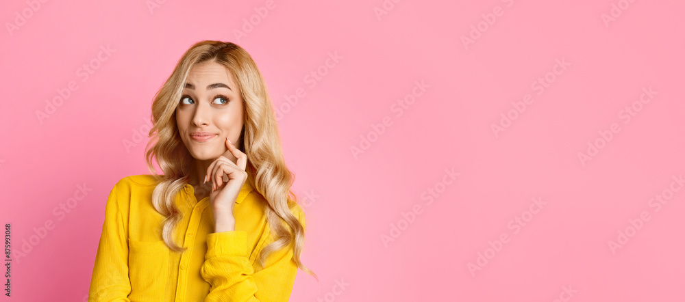 This image features a young woman with long blonde hair wearing a yellow shirt. She is standing in front of a pink background and is looking off to the side, appearing thoughtful. This image features a young woman with long blonde hair wearing a yellow shirt. She is standing in front of a pink background and is looking off to the side, appearing thoughtful.
