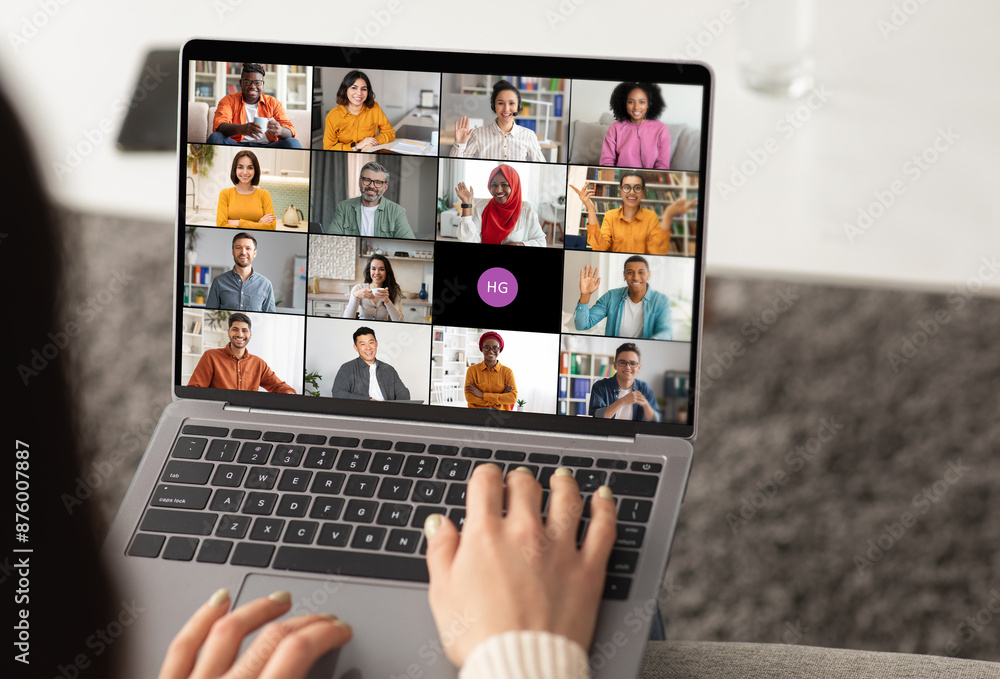Woman using a laptop to participate in an online video chat meeting. The screen displays several participants in a grid format, showcasing a diverse group of people. Woman using a laptop to participate in an online video chat meeting. The screen displays several participants in a grid format, showcasing a diverse group of people.