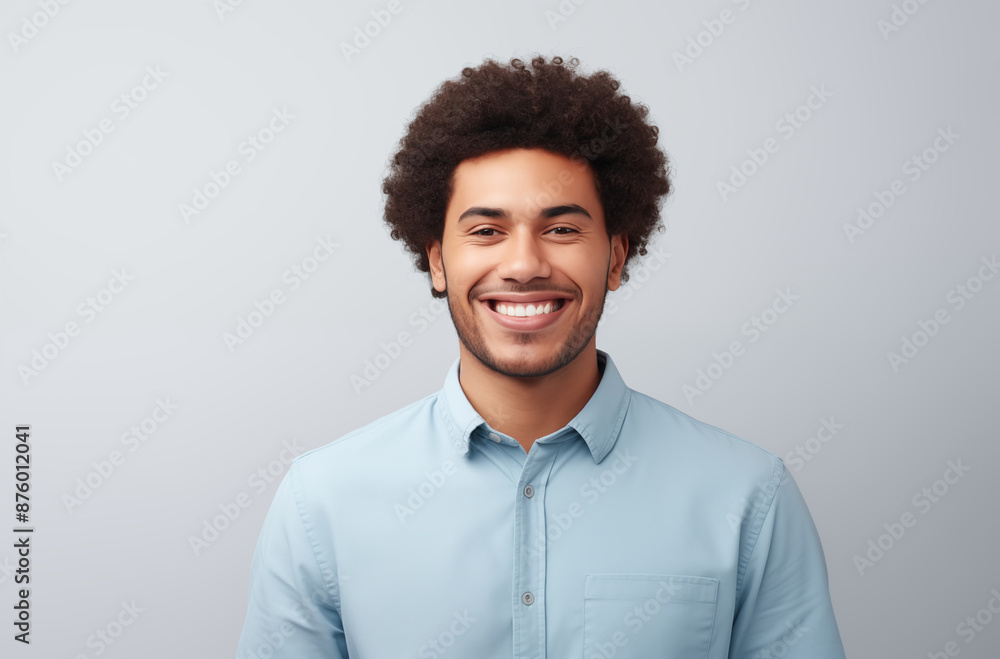 Young man with a cheerful smile and afro hairstyle, wearing a light blue shirt, standing against a light grey background Young man with a cheerful smile and afro hairstyle, wearing a light blue shirt, standing against a light grey background