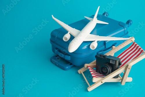 Travel suitcase, airplane, digital camera and red beach chair on blue background copy space. Travel abroad summer holiday vacation around the world, booking hotel or flight ticket, tourism concept. photo