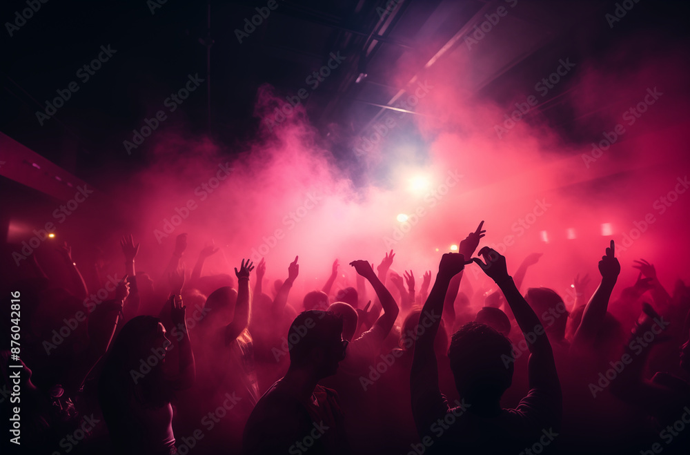 Large crowd of people dancing with raised hands in a nightclub filled with vibrant pink and purple lights and smoke Large crowd of people dancing with raised hands in a nightclub filled with vibrant pink and purple lights and smoke