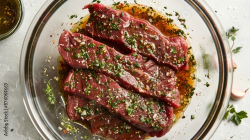 A juicy flank steak marinating in a bowl with herbs, olive oil, and garlic, ready for grilling.