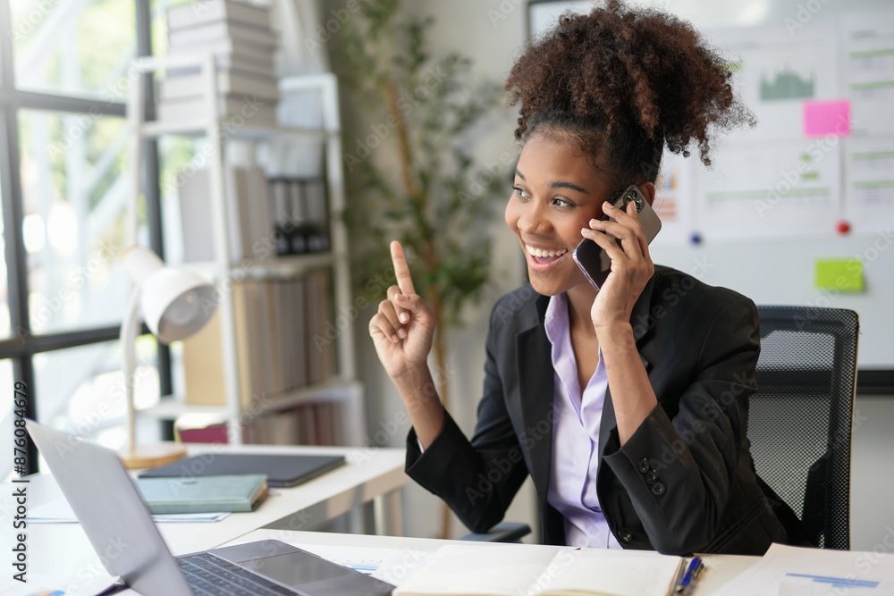Businesswoman smiling and pointing finger up while talking on phone at work Businesswoman smiling and pointing finger up while talking on phone at work