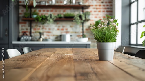 A rustic wooden table with a small green plant centerpiece in a modern, industrial-style dining area. The space features black ergonomic chairs and warm ambient lighting for a cozy atmosphere.