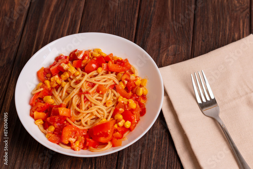 Tomato spaghetti in white plate on a wooden table. Tomato sauce pasta is classic italian cuisine dish. Popular italian food.