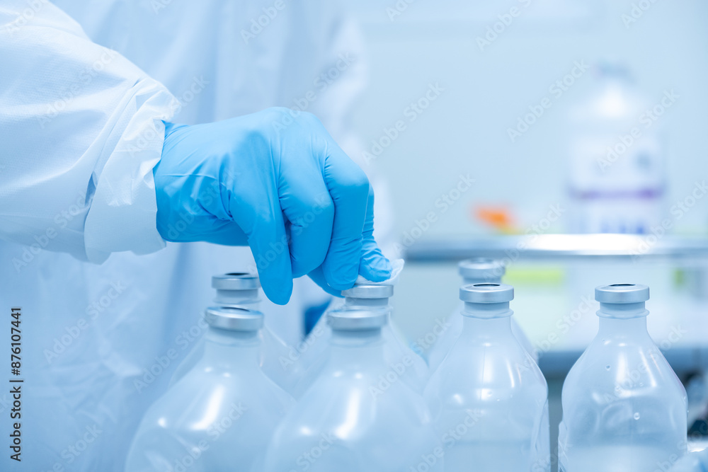 The doctor wearing blue gloves and uses a cotton swab to wipe off the normal saline solution before opening it to mix chemical medicines.Infection control concept. The doctor wearing blue gloves and uses a cotton swab to wipe off the normal saline solution before opening it to mix chemical medicines.Infection control concept.