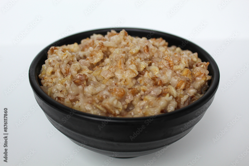Cooked plain rolled oat inside black bowl, Isolated on white background Cooked plain rolled oat inside black bowl, Isolated on white background