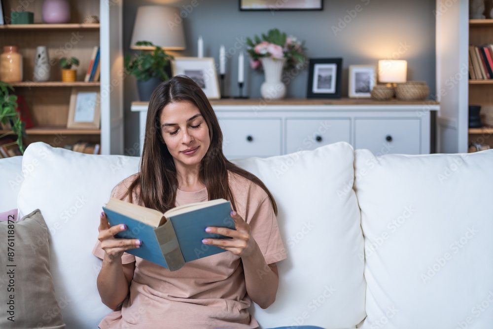 Young beautiful woman sitting at home reading a good love story book, daydreaming about perfect relationship and prince on a white horse. Female weekend activities read a book on sofa and imagining Young beautiful woman sitting at home reading a good love story book, daydreaming about perfect relationship and prince on a white horse. Female weekend activities read a book on sofa and imagining