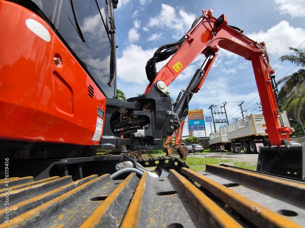 Red large excavators are stationed in a green field in front of a building Red large excavators are stationed in a green field in front of a building