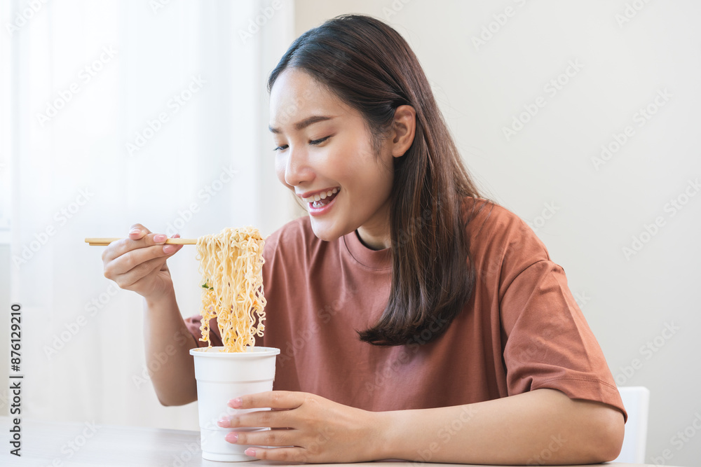 Happy temptation, attractive asian young student woman, cute girl using chopsticks eating instant ramen, noodles soup from a cup, cooking meal fast food lifestyle of traditional japanese person. Happy temptation, attractive asian young student woman, cute girl using chopsticks eating instant ramen, noodles soup from a cup, cooking meal fast food lifestyle of traditional japanese person.