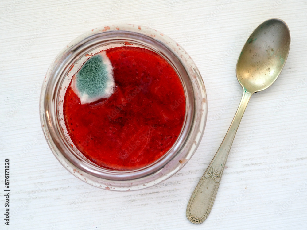 Moldy Strawberry Jam in a Glass Jar with Spoon on a Wooden Table Moldy Strawberry Jam in a Glass Jar with Spoon on a Wooden Table