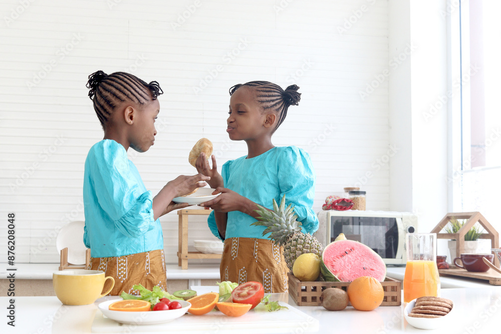 Twin sister girl with curly hair braid African hairstyle have meal together in kitchen. Happy kid bite bread croissant buns with her sibling. Cute children spending time together in family Twin sister girl with curly hair braid African hairstyle have meal together in kitchen. Happy kid bite bread croissant buns with her sibling. Cute children spending time together in family