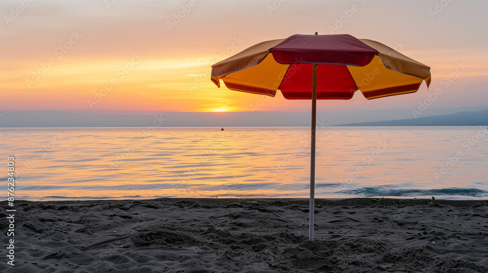 A red and yellow umbrella is on a beach at sunset A red and yellow umbrella is on a beach at sunset