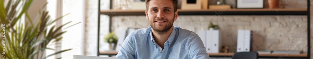 Fototapeta premium Portrait of a Successful and Confident Young Man in a Blue Shirt Working on a Laptop at Office Desk, Smiling at the Camera, Labor Day Overwork, AI-Generated High-Resolution Wallpaper