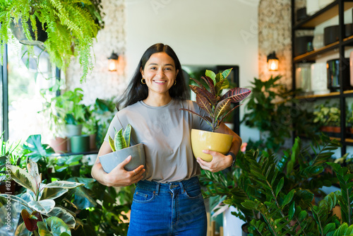 Fotografía Portrait of a joyful young woman shopping for houseplants at a garden center, ho