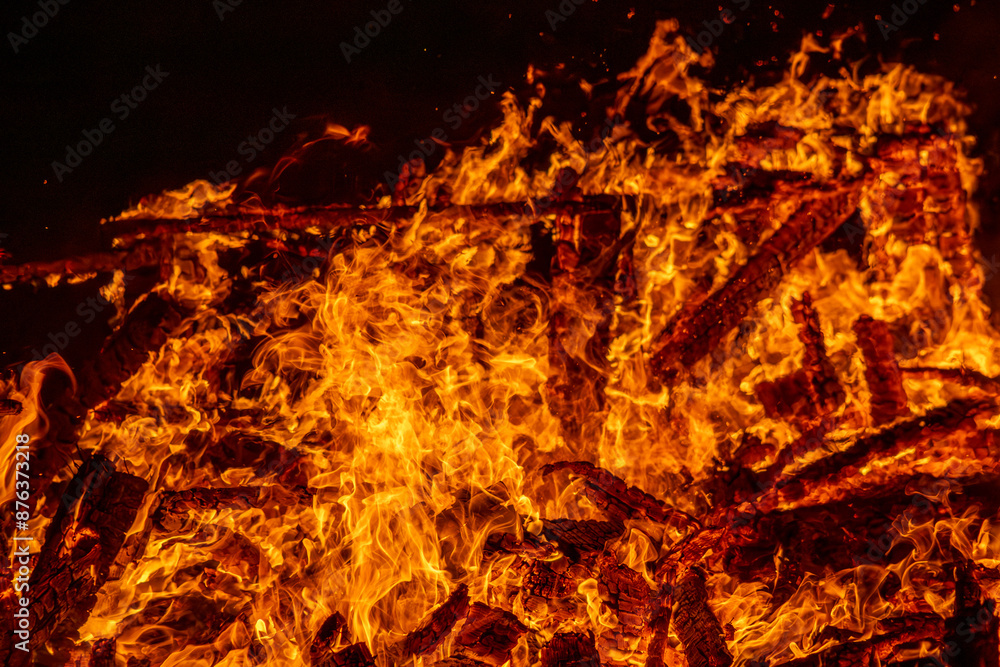 A dramatic image of a fierce fire burning intensely against the dark night sky. The bright orange and yellow flames highlight the raw energy and destructive power of the blaze. Copy space available. A dramatic image of a fierce fire burning intensely against the dark night sky. The bright orange and yellow flames highlight the raw energy and destructive power of the blaze. Copy space available.