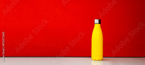 Slika na platnu Yellow steel thermo water bootle on red background
