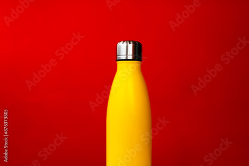 Fotografija Yellow steel thermo water bootle on red background.