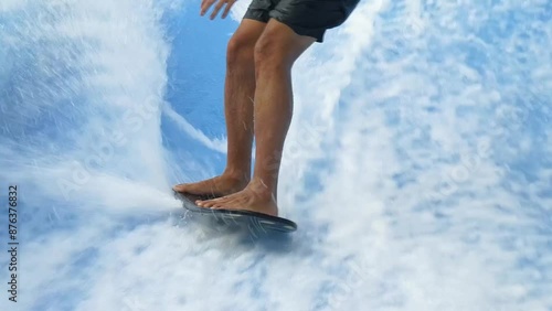 Young man surfing on a wave simulator at a water amusement park