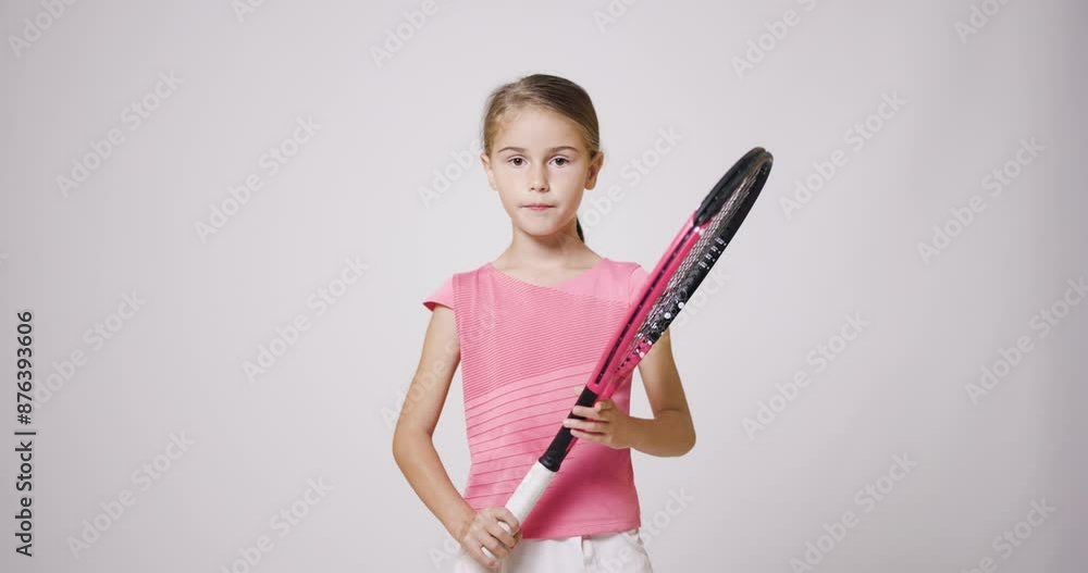 Young female tennis player holding a racket. Girl in pink sports outfit looking at camera. Young female tennis player holding a racket. Girl in pink sports outfit looking at camera.