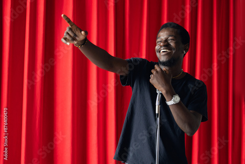 African american man comic with old microphone on theater stage on red curtains background. Concept banner standup comedian show