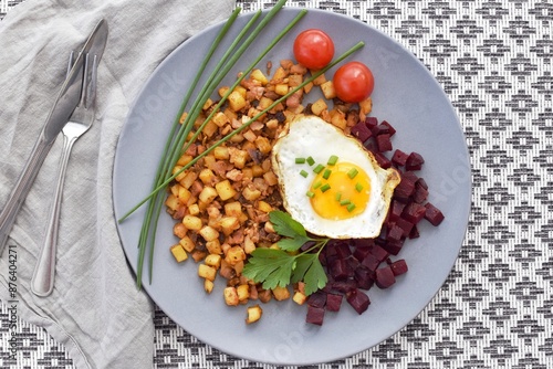 A traditional Scandinavian dish made from leftover chopped potatoes, onions and meat. Served with a fried egg and boiled beets. photo