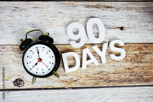 90 Days and alarm clcok alphabet letters on wooden background