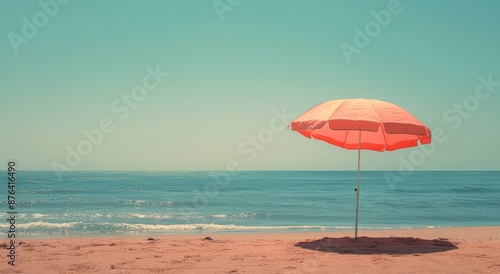 A Single Orange Beach Umbrella Stands Alone on a Sandy Shore photo