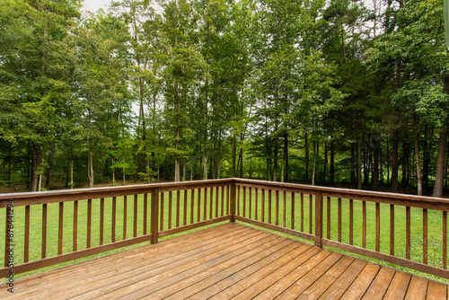 Wooden Deck Overlooking Green Backyard With Dense Forest In View photo