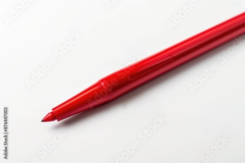 A single red pen resting on a white surface, ready for use