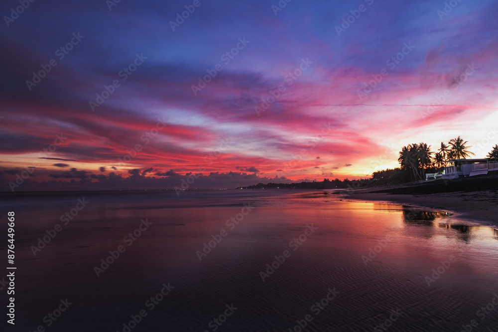 Naklejka premium Sunrise on the ocean beach. Beautiful landscape with pink sky with clouds. Tropical scenery, horizon with coastal view. The island of Bali in Indonesia. Natural background.