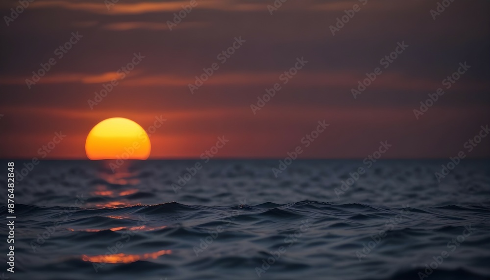 Out of focus sun setting over the ocean glowing orange with dark blue background Out of focus sun setting over the ocean glowing orange with dark blue background