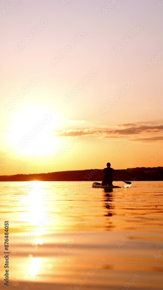 Beautiful sunset on the river on summer day. Man stands in his knees on sup board rowing by the waterscape. Vertical video. Beautiful sunset on the river on summer day. Man stands in his knees on sup board rowing by the waterscape. Vertical video.