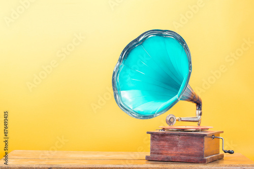 Vintage antique gramophone phonograph turntable with mint blue horn on oak table front yellow background. Retro style filtered photo