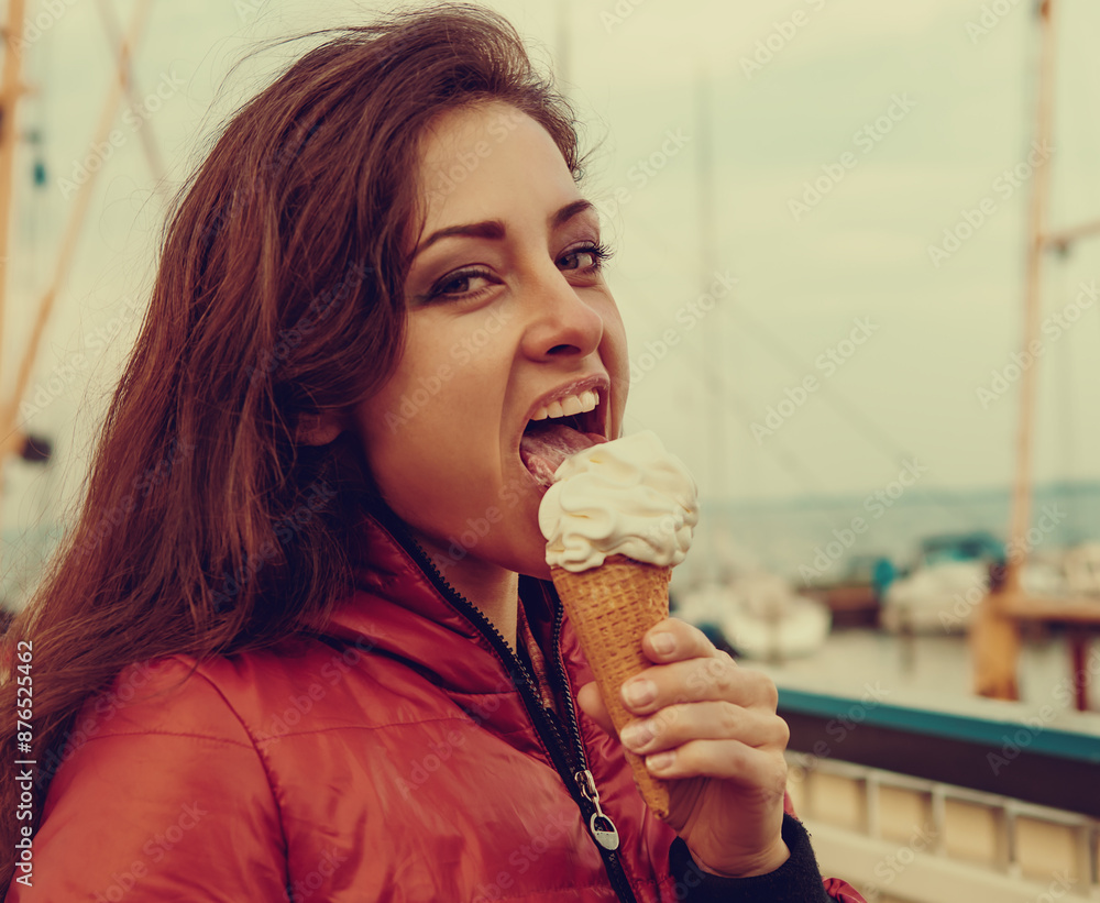 Sexy happy fun brunette woman eating tasty ice cream on the embankment of ocean and blue sky day background. Closeup toned color vintage Sexy happy fun brunette woman eating tasty ice cream on the embankment of ocean and blue sky day background. Closeup toned color vintage