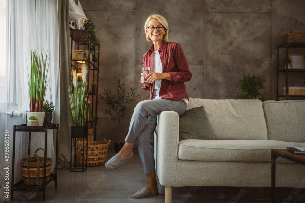 Obraz premium Portrait of beautiful mature senior woman sit and hold glass of water