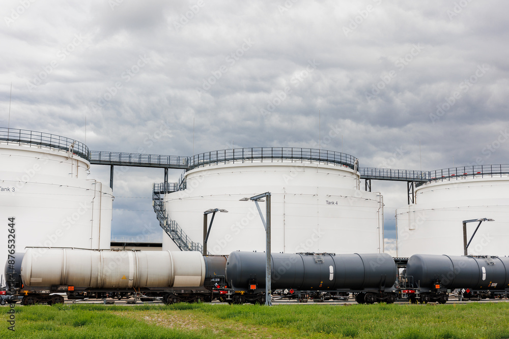 Row many large industrial fuel storage white tanks cloudy overcast sky background day. Oil storage refinery depot liquid facilities. Energy hazmat railroad transportation storage and distribution Row many large industrial fuel storage white tanks cloudy overcast sky background day. Oil storage refinery depot liquid facilities. Energy hazmat railroad transportation storage and distribution