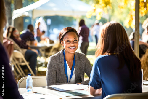 African American female hr recruiter's lively engagement, interview with potential employees at an outdoor job career fair. Cheerful ambiance of a sunny setting on background. Concept of Labor Day