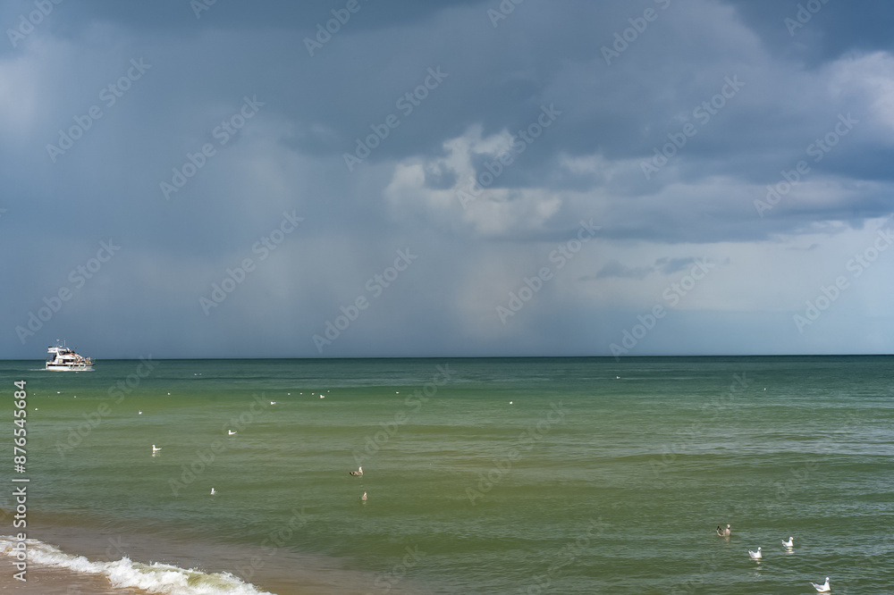 Ship in the distance sailing on blue water in rainy weather. Unusual colour of the sea. Baltic Sea. Poland. . High quality photo Ship in the distance sailing on blue water in rainy weather. Unusual colour of the sea. Baltic Sea. Poland. . High quality photo