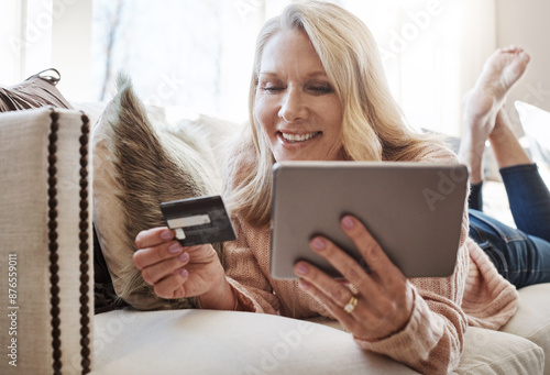 Woman, credit card and tablet on couch for online shopping, sale and deal on web store in house. Mature person, relax and easy payment for bills, discount and fintech app for ecommerce in Munich photo