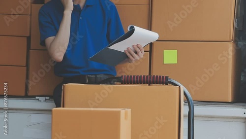 Young cheerful delivery man with parcel near car full of cardboard boxes, full length shot. Shipping service concept photo